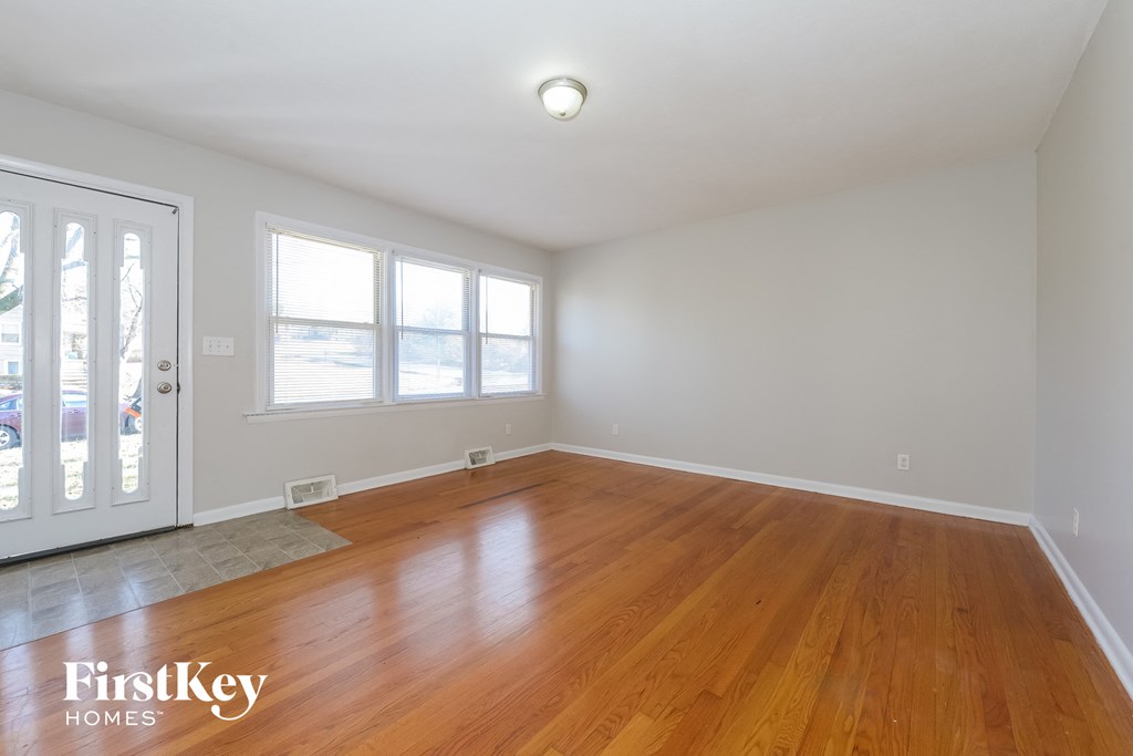 an empty living room with wood floors and a door to a balcony