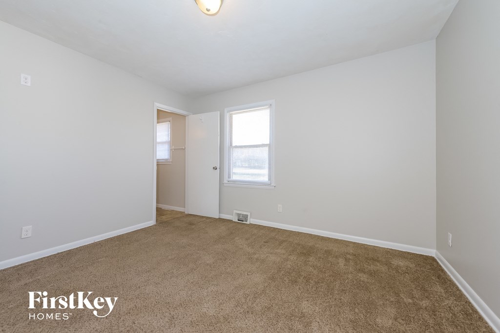 a bedroom with white walls and carpet and a window