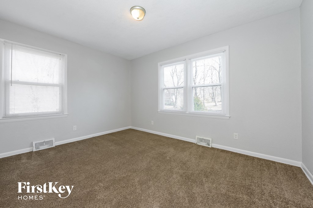 the living room of a home with carpet and two windows