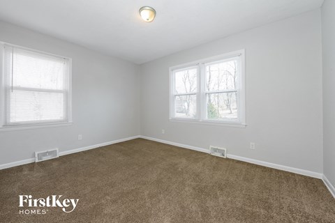 the living room of a home with carpet and two windows
