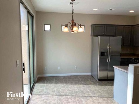 A kitchen with a refrigerator, cabinets, and a chandelier.