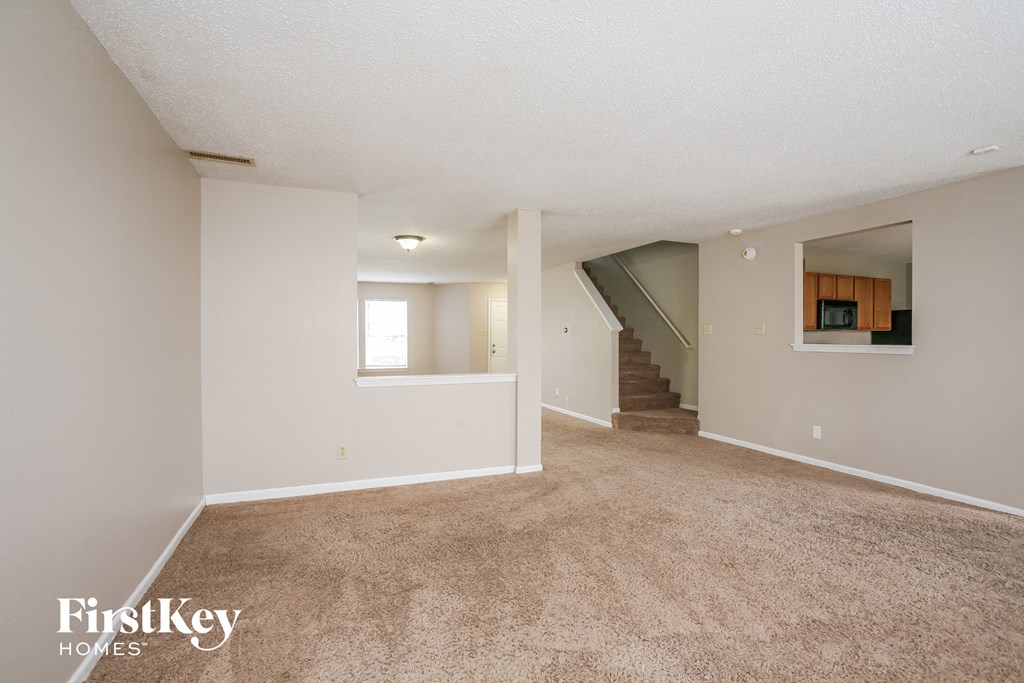 A spacious room with a staircase leading to another room.