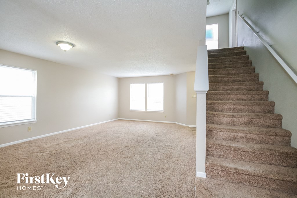 A room with a staircase and two windows.
