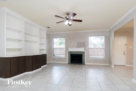 A spacious living room with a fireplace and a ceiling fan.