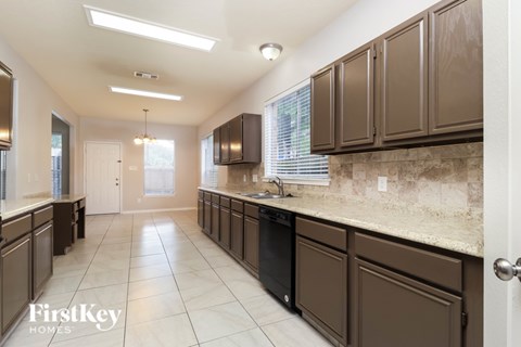 A kitchen with brown cabinets and a black dishwasher.