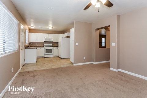 A spacious room with a kitchen area and a ceiling fan.