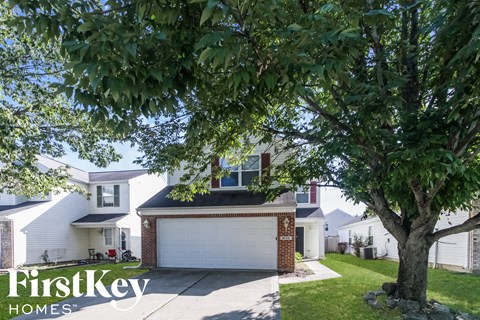 A tree stands in front of a house with a garage.