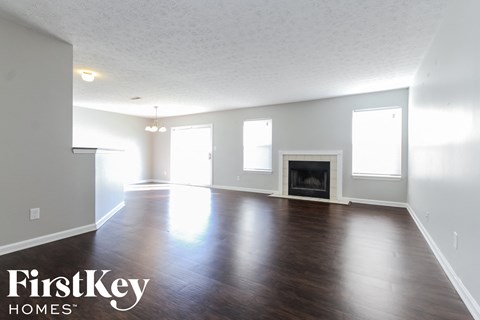 A spacious room with a fireplace and wooden floors.