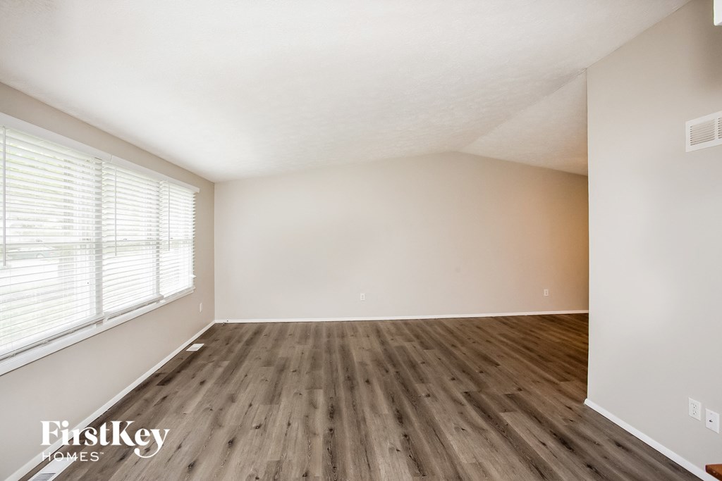 a spacious living room with wood flooring and a large window