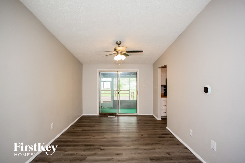 a spacious living room with white walls and a ceiling fan
