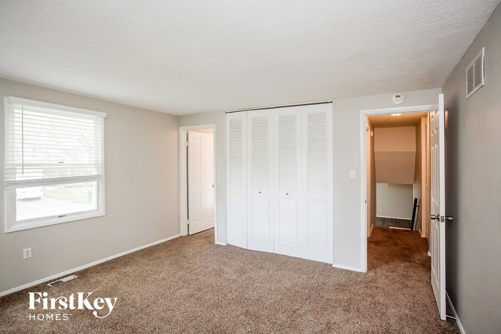 a bedroom with white closets and a carpeted floor
