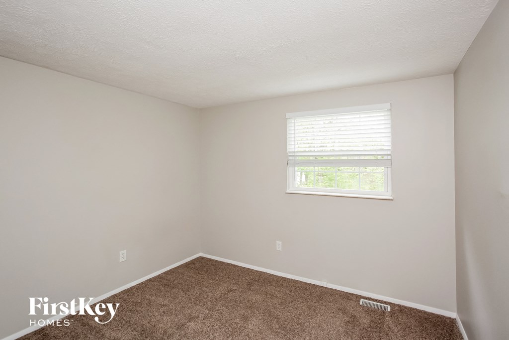a small room with carpet and a window