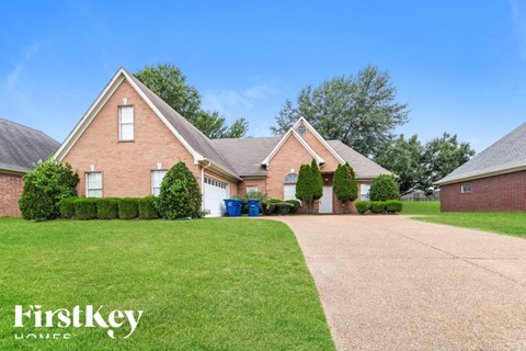 a brick house with a driveway and a lawn