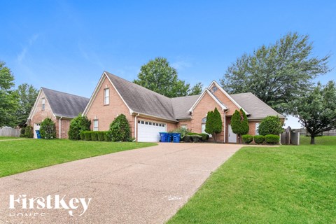 a large brick house with a driveway and lawn