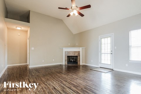 a empty living room with a ceiling fan and a fireplace