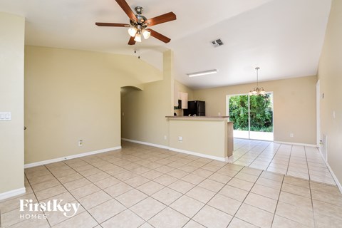 A spacious room with a ceiling fan and a bar area.