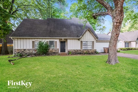 a white house with a yard and a tree