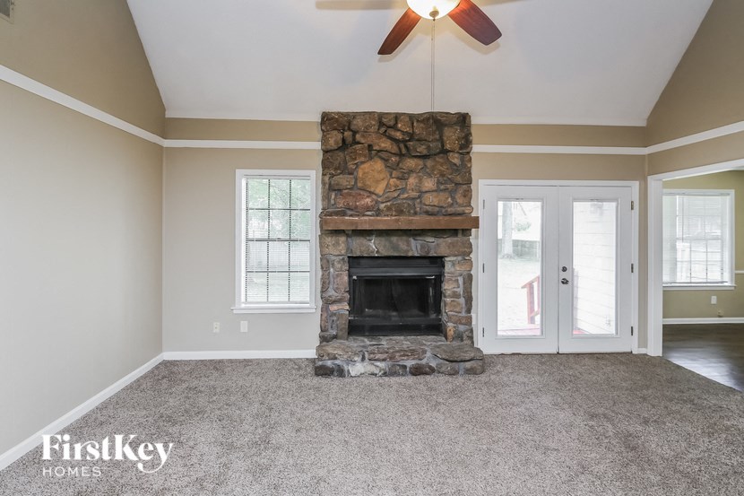 a living room with a stone fireplace and a ceiling fan