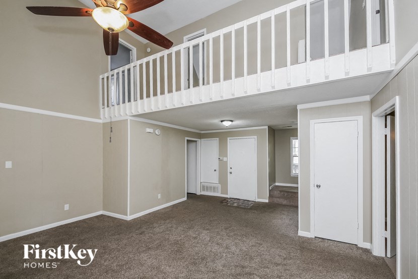 an empty living room with a ceiling fan and a staircase