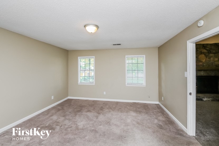 an empty living room with a fireplace and carpet