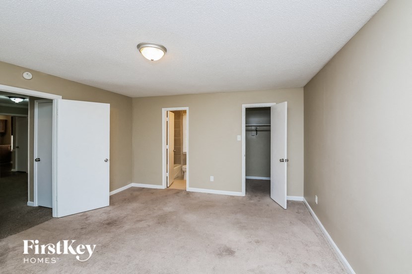 an empty living room with three doors and a carpeted floor