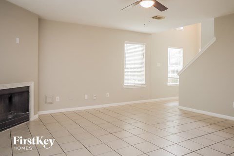 an empty living room with a fireplace and tiled floor