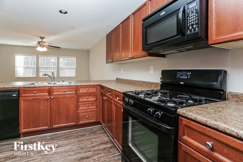 a kitchen with black appliances and wooden cabinets and granite counter tops