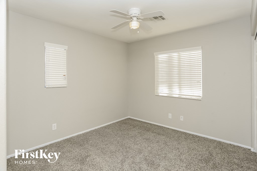 a empty room with a ceiling fan and two windows