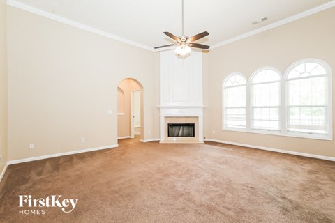 an empty living room with a ceiling fan and a fireplace