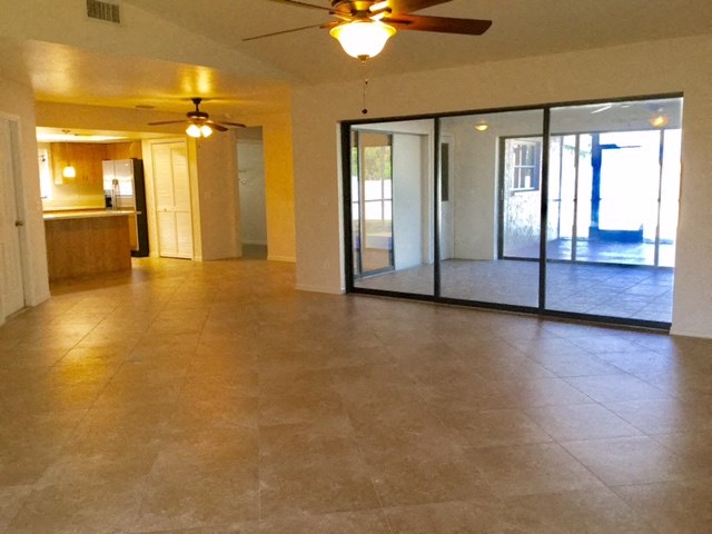an empty living room with a ceiling fan