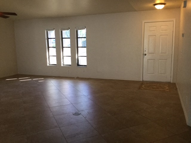 an empty living room with a white door and tiled floors