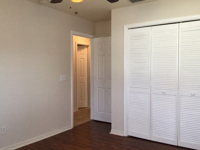 an empty room with white closet doors and a door to a hallway