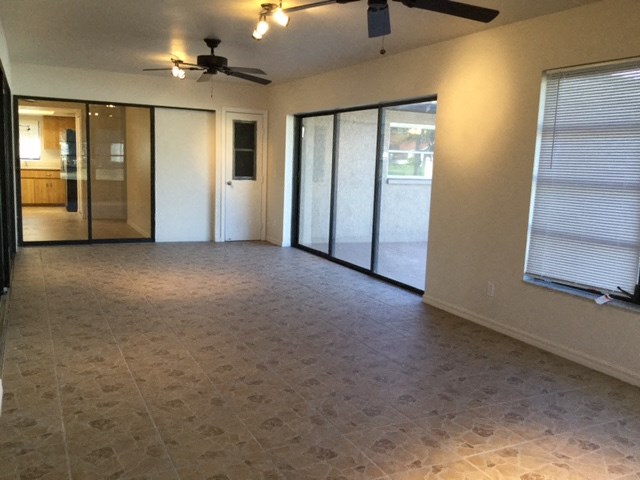 an empty living room with a ceiling fan and sliding glass doors