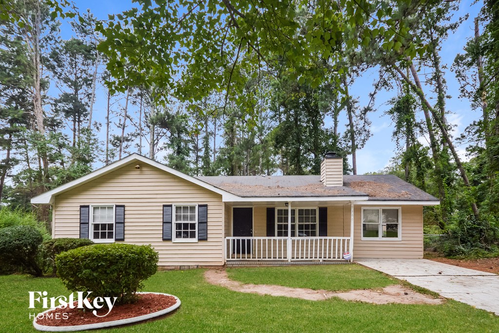 A house with a porch and a tree in front of it.
