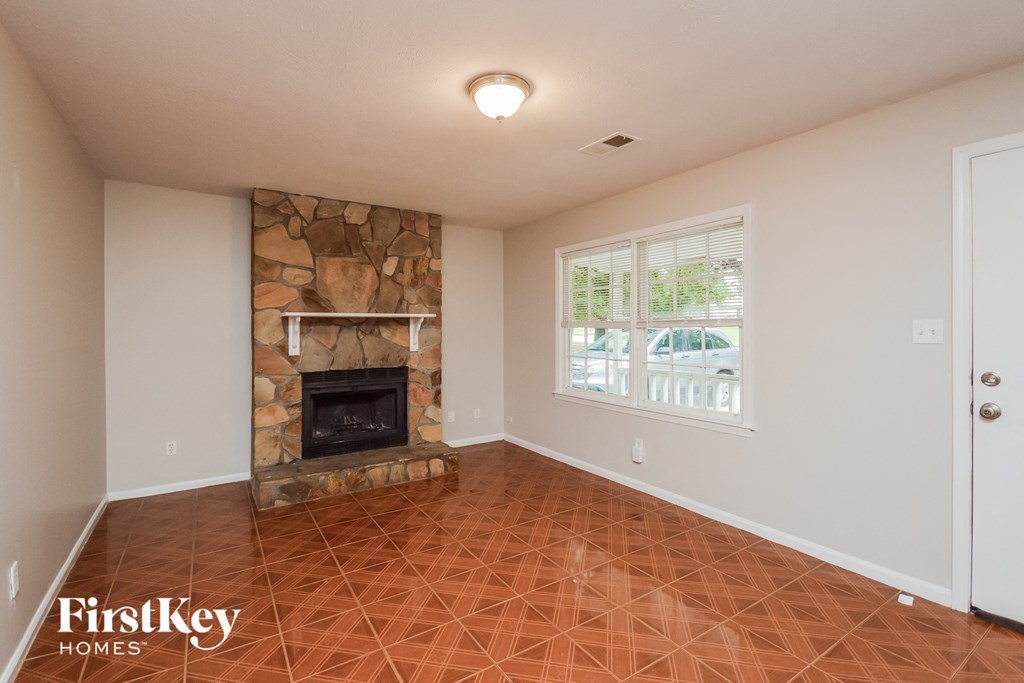 A room with a stone fireplace and tile flooring.