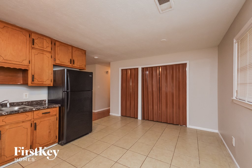A kitchen with wooden cabinets and a black refrigerator.