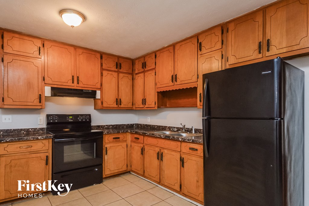 A kitchen with wooden cabinets and a black refrigerator.