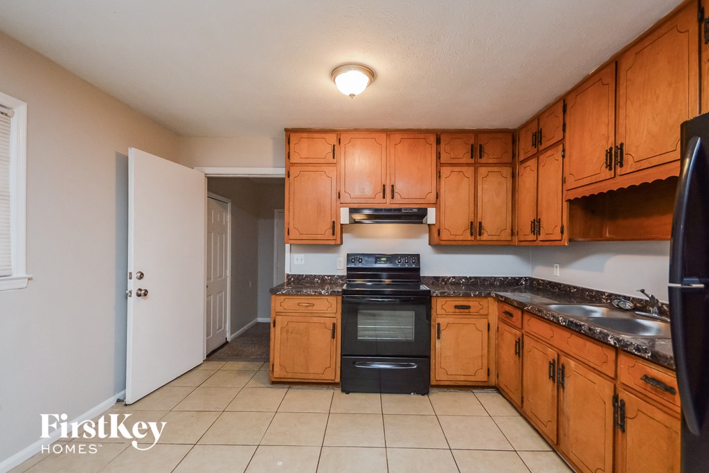 A kitchen with wooden cabinets and a black refrigerator.