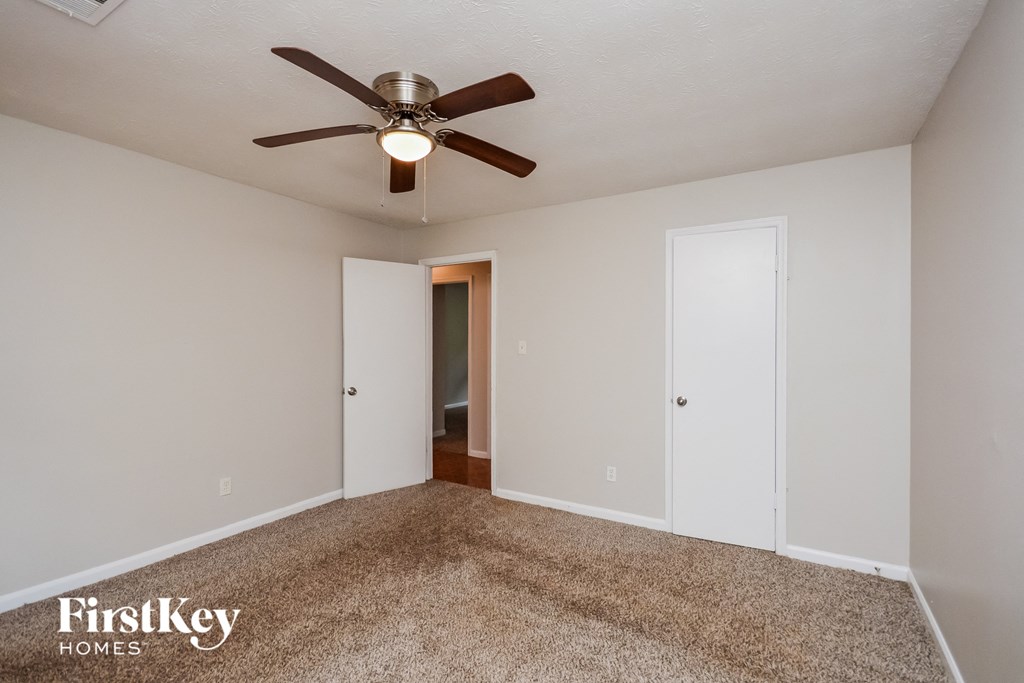 A room with a ceiling fan and carpeted floor.