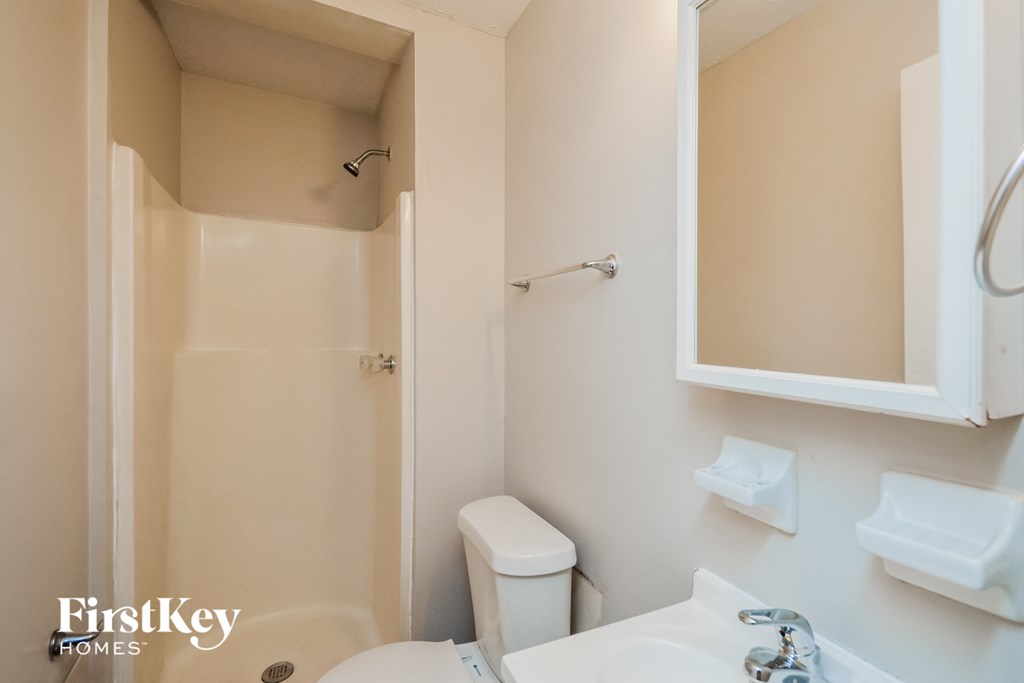 A white bathroom with a toilet, sink and shower.