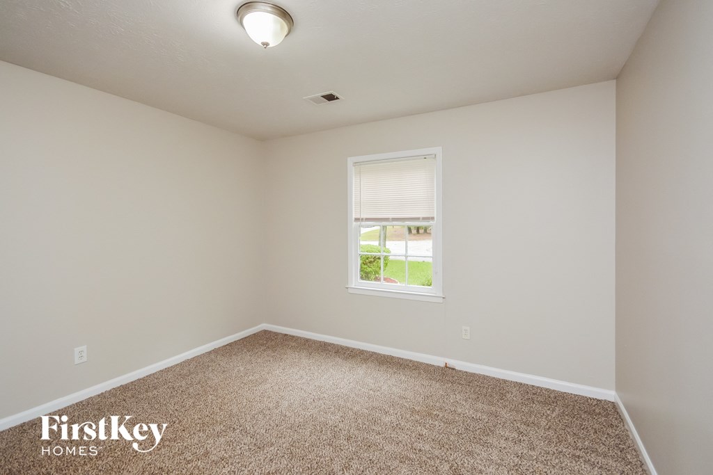 A carpeted room with a window and a FirstKey Homes logo.