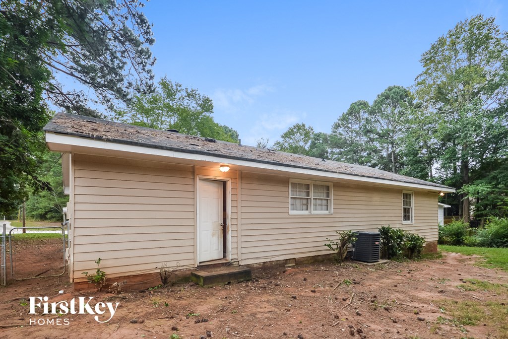 A small house with a porch and a tree in front.