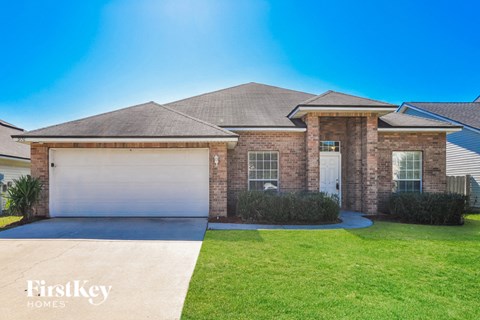 a brick house with two garage doors and a lawn