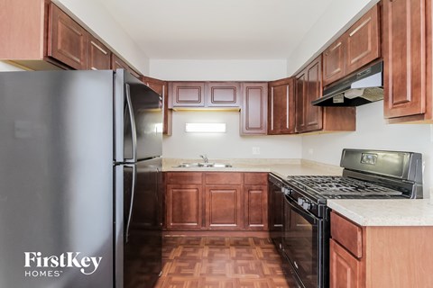 A kitchen with wooden cabinets and a black fridge.