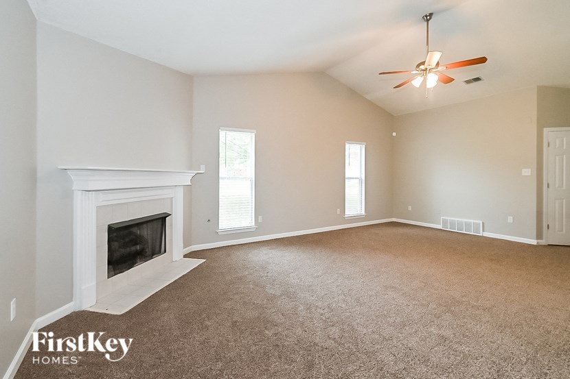 an empty living room with a fireplace and a ceiling fan