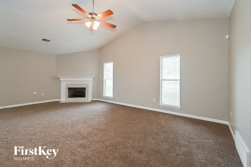 an empty living room with a ceiling fan and a fireplace