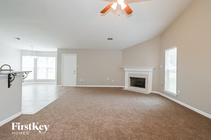 an empty living room with a fireplace and a ceiling fan