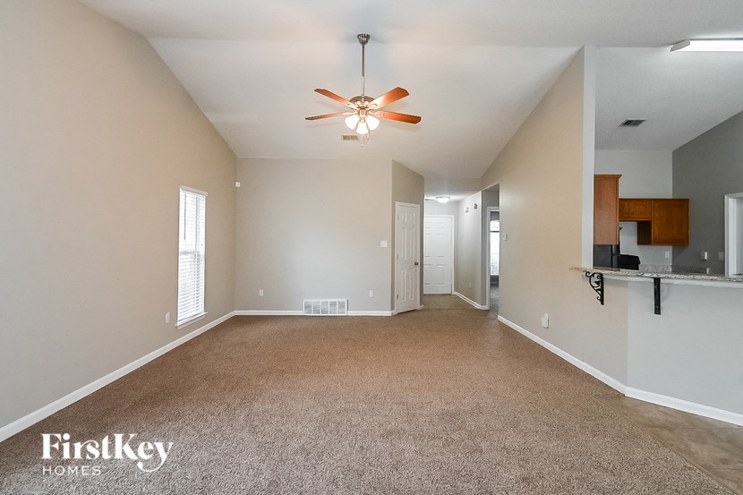an empty living room with a ceiling fan