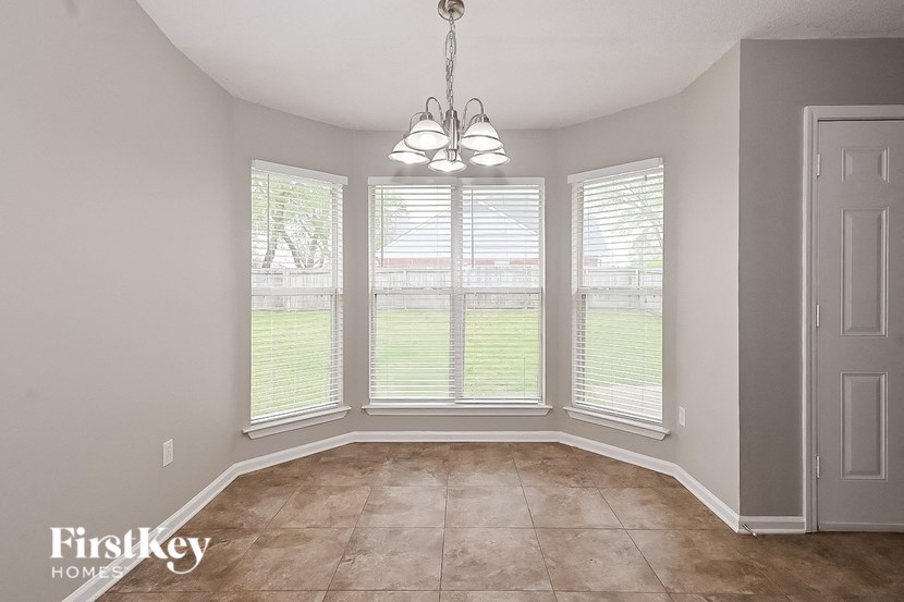 an empty living room with three windows and tiled floors