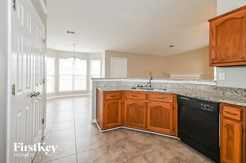 an empty kitchen with wooden cabinets and a black dishwasher